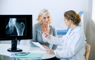 woman and doctor completing a osteoporosis diagnosis in the doctors office pointing to xray